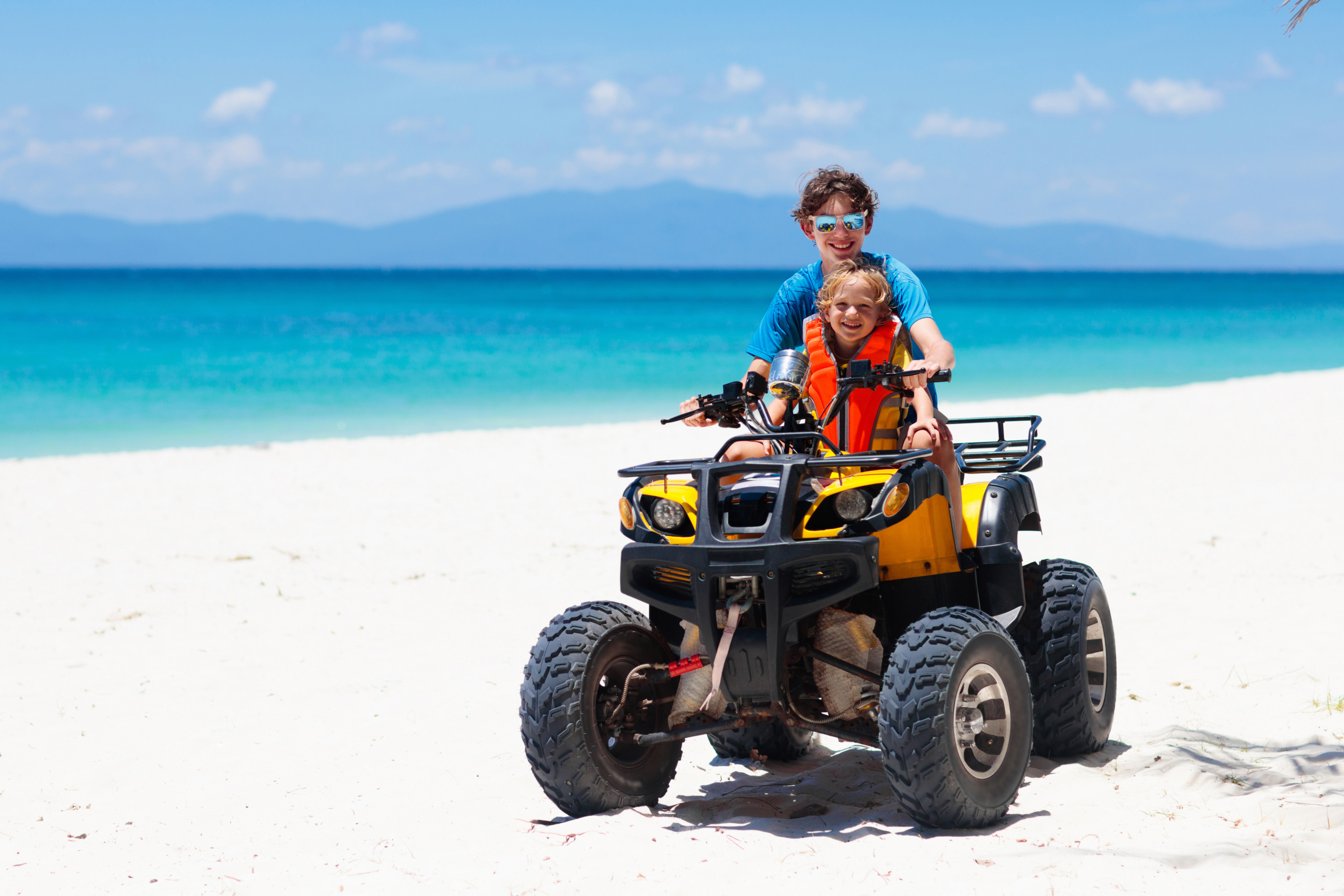 Teenager,And,His,Little,Brother,Riding,Quad,Bike,On,Tropical
